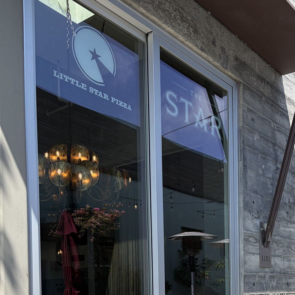 Storefront glass at Little Star Pizza cleaned by Politrons, with the painted logo and the dining room chandelier showing clearly through the pane